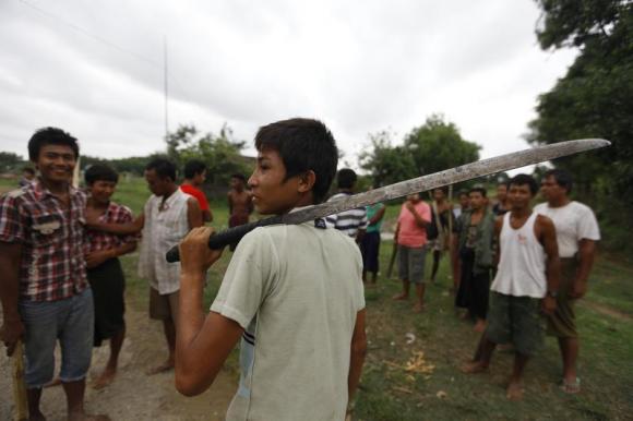 A Buddhist man holds a machete as he and other members of the community guard their homes in Sittwe June 9, 2012.