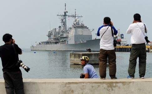 Members of the press take photos of the US guided missile cruiser USS Cowpens docked in Manila bay. Photo: AFP