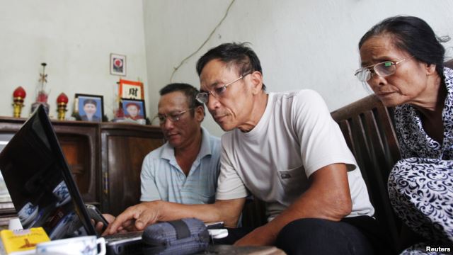 Veteran Le Dung (C) reads articles on the Internet with Dang Van Dat (L) and Tran Thi Thanh Kiem (R) at his house in Van Giang district, outside Hanoi, Vietnam.