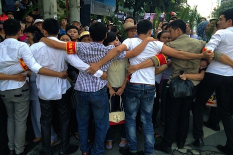 Vietnamese plainclothes policemen in this 2013 file photo form a human chain to prevent hundreds of protestors from approaching the People's Court where a Catholic Vietnamese activist lawyer Le Quoc Quan was facing trial. (Photo by Cat Barton/ AFP)