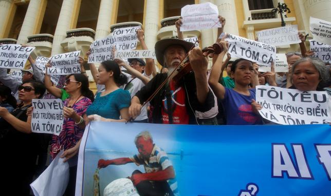 Violinist Ta Tri Hai performs in front of demonstrators who are holding signs during a protest in Hanoi, Vietnam May 1, 2016 against a unit of Taiwan’s Formosa Plastics, a firm they blame for causing an environmental disaster and the death of large numbers of fish in central...
